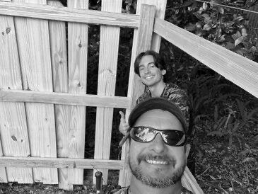 Tommy and one of his sons beside a custom wood fence
