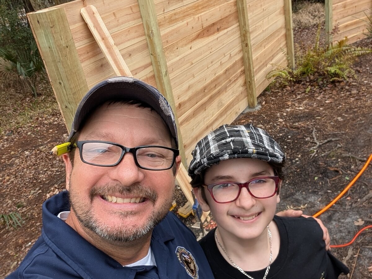 Tommy and one of his sons in front of a newly built wood fence