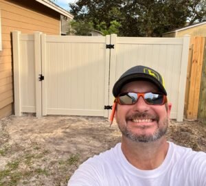 Tommy beside a tan vinyl privacy fence and matching gate in Jacksonville